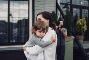 une femme tenant un bébé devant un immeuble