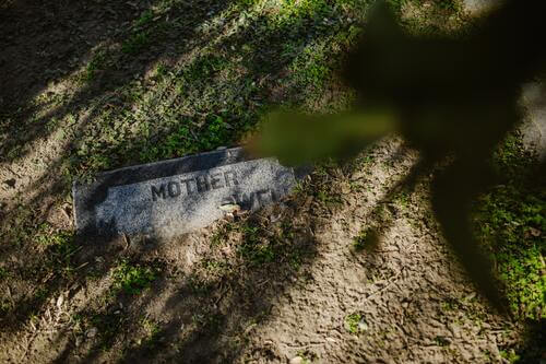 Halb vergrabener Grabstein mit der Inschrift „Mutter“.
