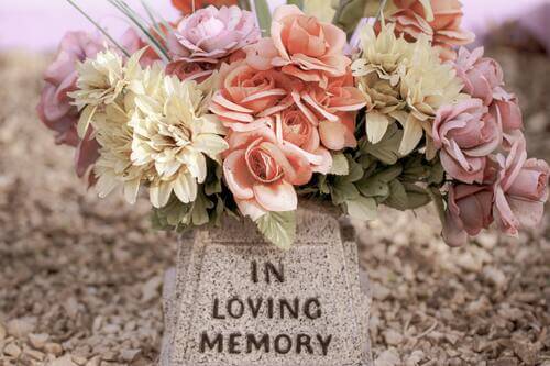 Small stone marker inscribed with in loving memory with flowers on top