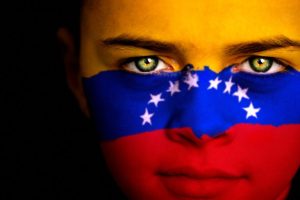 Chica joven con una bandera venezolana en su rostro.